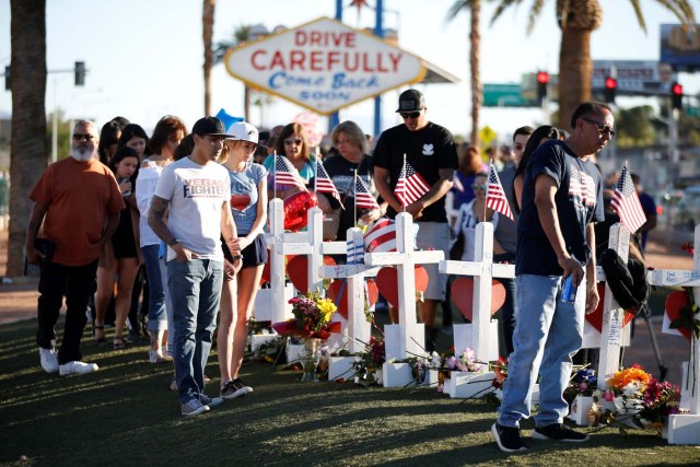 People gather to look at white crosses set up for the victims of the Route 91 Harvest music festival mass shooting in Las Vegas, Nevada, U.S., October 6, 2017. REUTERS/Chris Wattie