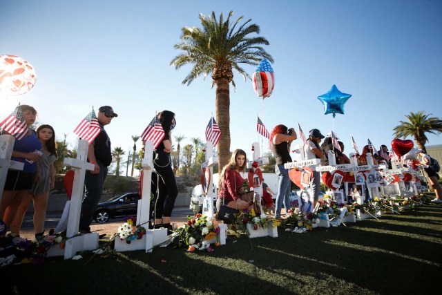 A woman places a flower in front of one of many white crosses set up for the victims of the Route 91 Harvest music festival mass shooting in Las Vegas, Nevada, U.S., October 6, 2017. REUTERS/Chris Wattie