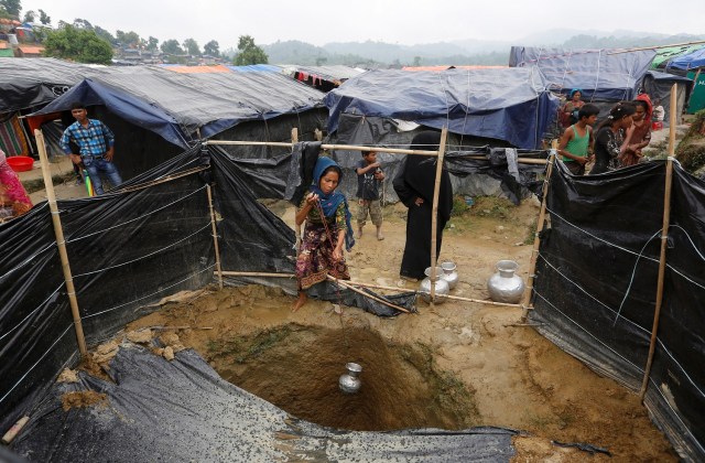 Una mujer refugiada rohingya recoge agua de un pozo poco profundo, excavado en la arena fuera de su refugio en el campo de refugiados de Uchiprang, cerca de Cox's Bazar, Bangladesh 29 de octubre de 2017. REUTERS / Adnan Abidi