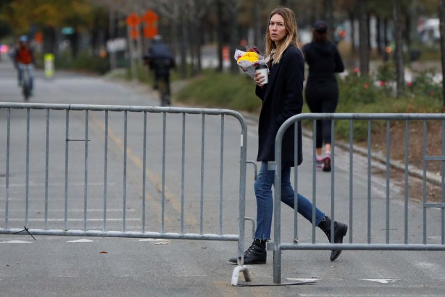 A woman, who a NYC Park ranger said asked where she could lay flowers for victims of Tuesday's attack, walks by a police barricade on the bike path next to West Street a day after a man driving a rented pickup truck mowed down pedestrians and cyclists on a bike path alongside the Hudson River in New York City, U.S. November 1, 2017. REUTERS/Shannon Stapleton