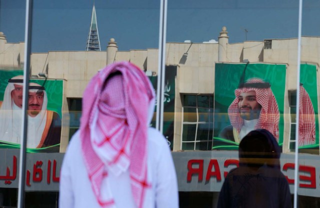 Pictures of Saudi Arabia's King Salman bin Abdulaziz Al Saud and Crown Prince Mohammed bin Salman are reflected in a window as people arrive at a company in Riyadh, Saudi Arabia, November 9, 2017. REUTERS/Faisal Al Nasser NO RESALES. NO ARCHIVES
