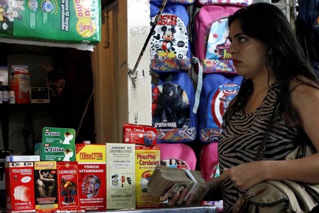 A woman holds a stack of bolivar notes in a stall selling medicines at a market in Rubio, Venezuela December 5, 2017. Picture taken December 5, 2017. REUTERS/Carlos Eduardo Ramirez