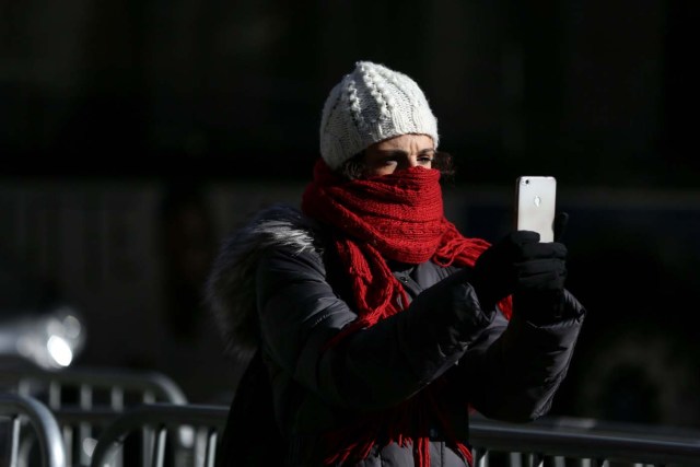 A woman takes a picture as she bundles up against the cold temperature in Times Square in Manhattan, New York, U.S., December 28, 2017. REUTERS/Amr Alfiky