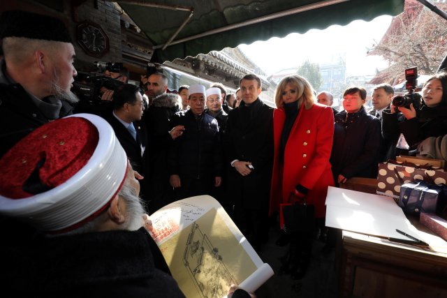 French President Emmanuel Macron (C) and his wife Brigitte Macron (R) are presented with a gift from a local elderly iman during a visit to the Great Mosque of Xian in the northern Chinese city of Xian in Xian, Shaanxi province, China January 8, 2018. REUTERS/Ludovic Marin/Pool