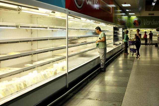 A man selects deli from a partially empty refrigerator at a supermarket in San Cristobal, Venezuela January 16, 2018. REUTERS/Carlos Eduardo Ramirez