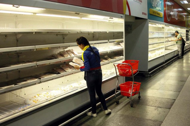 A woman selects deli from a partially empty refrigerator at a supermarket in San Cristobal, Venezuela January 16, 2018. REUTERS/Carlos Eduardo Ramirez