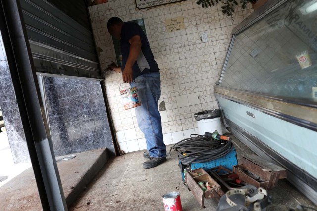 A worker paints a security shutter after repairing it at a bakery in Caracas, Venezuela January 16, 2018. Picture taken January 16, 2018. REUTERS/Marco Bello