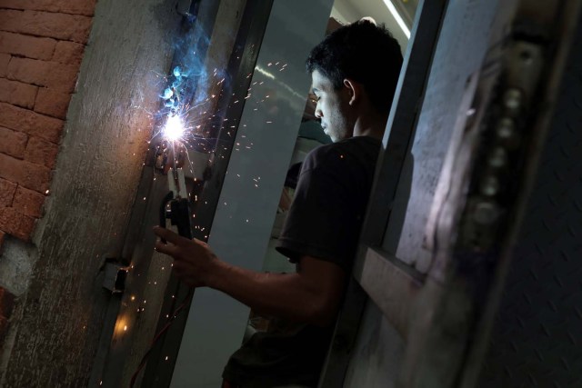 A worker welds a security gate at a shoe store in downtown Caracas, Venezuela January 16, 2018. Picture taken January 16, 2018. REUTERS/Marco Bello