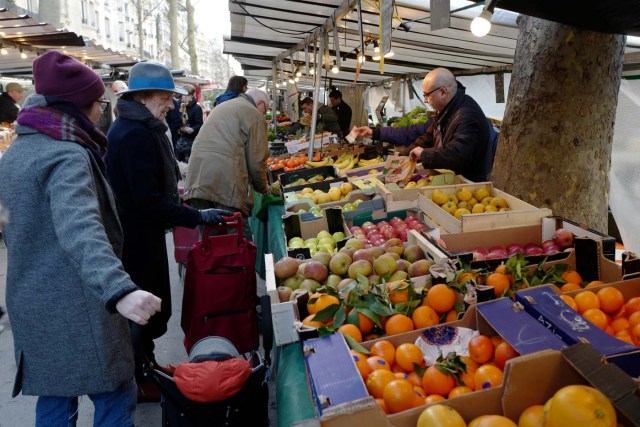 People shop fruits at the bio market at Boulevard Raspail in Paris, on Febuary 16, 2018. / AFP PHOTO / Ludovic MARIN