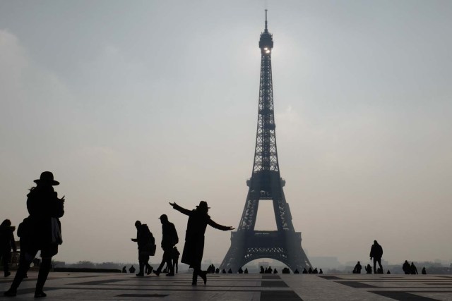 The silhouette of a woman is seen as she poses next to the Eiffel Tower in Paris on February 21, 2018. / AFP PHOTO / Ludovic MARIN