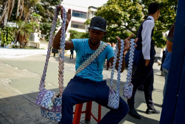 Wilmer Rojas, 25, shows the purses he sewn up, using Bolivar bills in Caracas, on January 30, 2018. A young Venezuelan tries to make a living out of devalued Bolivar banknotes by making crafts with them. / AFP PHOTO / FEDERICO PARRA