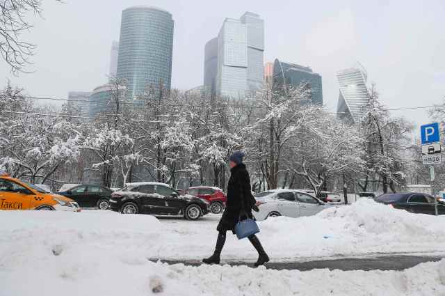 A woman walks along a street after a heavy snowfall, with the Moscow International Business Center also known as "Moskva-City" seen in the background, in Moscow, Russia February 5, 2018. REUTERS/Maxim Shemetov