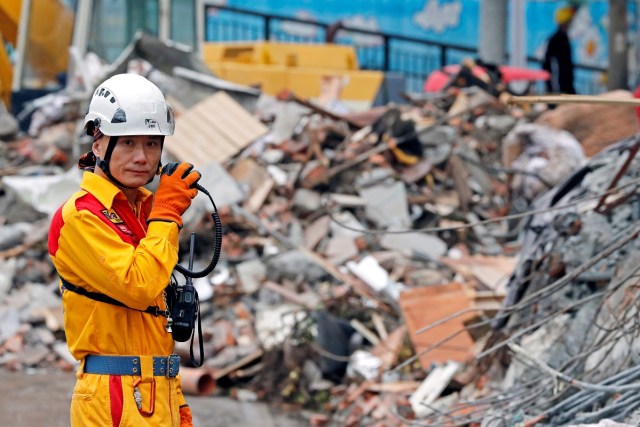 A rescuer speaks on the radio as he searches for survivors at collapsed building after an earthquake hit Hualien, Taiwan February 8, 2018. REUTERS/Tyrone Siu