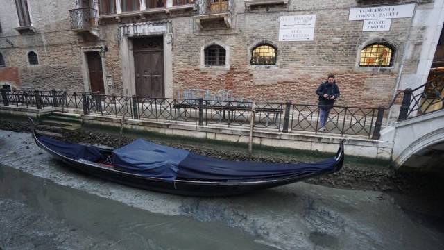 Una góndola permanece amarrada en un canal prácticamente sin agua en Venecia. (Efe)