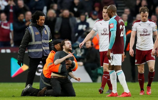 Soccer Football - Premier League - West Ham United vs Burnley - London Stadium, London, Britain - March 10, 2018 Fan is tackled by stewards after invading the pitch REUTERS/David Klein EDITORIAL USE ONLY. No use with unauthorized audio, video, data, fixture lists, club/league logos or "live" services. Online in-match use limited to 75 images, no video emulation. No use in betting, games or single club/league/player publications. Please contact your account representative for further details. TPX IMAGES OF THE DAY