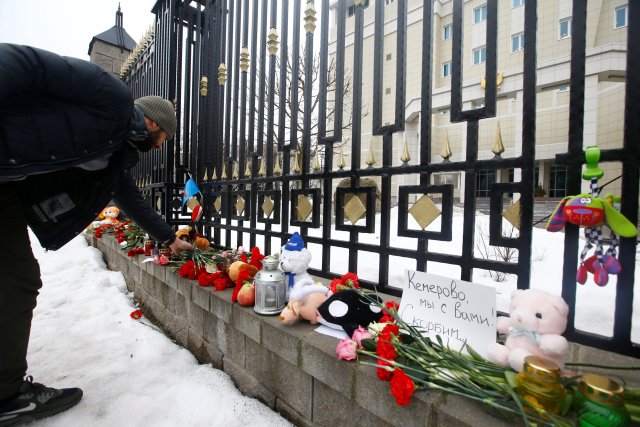 Un hombre coloca flores para conmemorar a las víctimas del incendio del centro comercial en Kemerovo, en la embajada rusa en Minsk, Bielorrusia el 27 de marzo de 2018. El letrero dice: "Kemerovo, estamos con usted. Estamos de luto". REUTERS / Vasily Fedosenko
