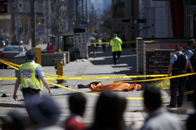 TORONTO, ON - APRIL 23: A tarp lays on top of a body on Yonge St. at Finch Ave. after a van plowed into pedestrians on April 23, 2018 in Toronto, Canada. A suspect is in custody after a white van collided with multiple pedestrians. Cole Burston/Getty Images/AFP