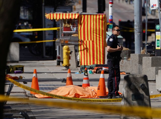 A police officer stands next to a victim of an incident where a van struck multiple people at a major intersection in Toronto's northern suburbs in Toronto, Ontario, Canada, April 23, 2018. REUTERS/Carlo Allegri