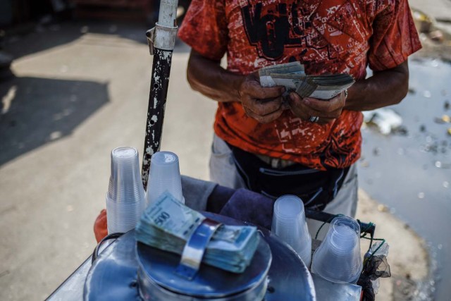 A peddler counts money in a street in Maracaibo, Venezuela on May 3, 2018. Amid blackouts, skyrocketing prices, shortage of food, medicine and transportation, Venezuelans go to elections next May 20 anguished to survive one of the worst crisis in the oil country. / AFP PHOTO / Federico PARRA