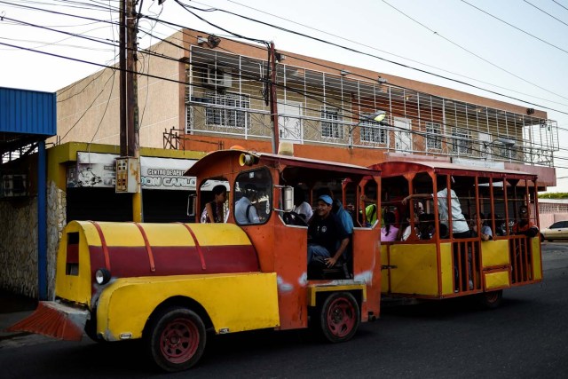 People travel in a children's train due to the lack of public transport on May 2, 2018, in Maracaibo, Venezuela. Amid blackouts, skyrocketing prices, shortage of food, medicine and transportation, Venezuelans go to elections next May 20 anguished to survive one of the worst crisis in the oil country. / AFP PHOTO / Federico PARRA