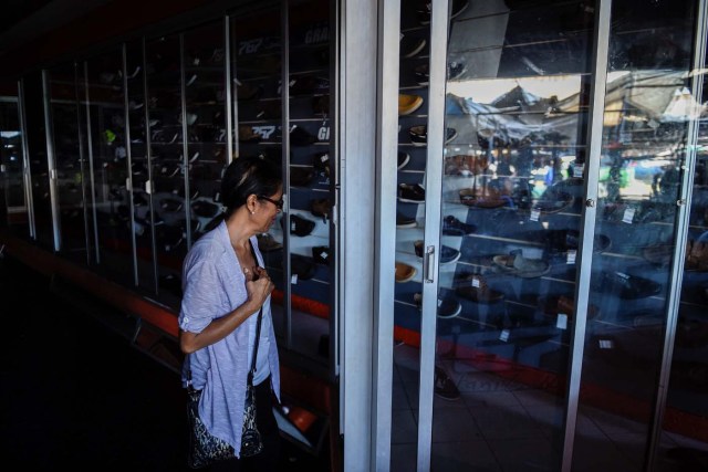 A woman looks at shoes in a store during a power outage in Maracaibo, Venezuela on May 3, 2018. Amid blackouts, skyrocketing prices, shortage of food, medicine and transportation, Venezuelans go to elections next May 20 anguished to survive one of the worst crisis in the oil country. / AFP PHOTO / Federico PARRA