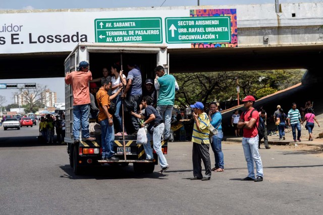 People travel on a private truck used as a means of transportation in Maracaibo, Venezuela on May 3, 2018. Amid blackouts, skyrocketing prices, shortage of food, medicine and transportation, Venezuelans go to elections next May 20 anguished to survive one of the worst crisis in the oil country. / AFP PHOTO / Federico PARRA