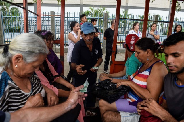 A man charges tickets to commuters using a children's train due to the lack of means of transportation on May 2, 2018, in Maracaibo, Venezuela. Amid blackouts, skyrocketing prices, shortage of food, medicine and transportation, Venezuelans go to elections next May 20 anguished to survive one of the worst crisis in the oil country. / AFP PHOTO / Federico PARRA