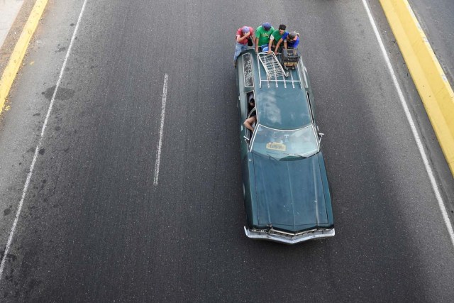 People travel on a private car used as a means of transportation in Maracaibo, Venezuela on May 3, 2018. Amid blackouts, skyrocketing prices, shortage of food, medicine and transportation, Venezuelans go to elections next May 20 anguished to survive one of the worst crisis in the oil country. / AFP PHOTO / Federico PARRA