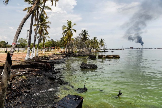 Remains of oil are seen at the shore of Maracaibo lake near to an oil refinery, on May 2, 2018 in Maracaibo, Venezuela. Amid blackouts, skyrocketing prices, shortage of food, medicine and transportation, Venezuelans go to elections next May 20 anguished to survive one of the worst crisis in the oil country. / AFP PHOTO / Federico PARRA
