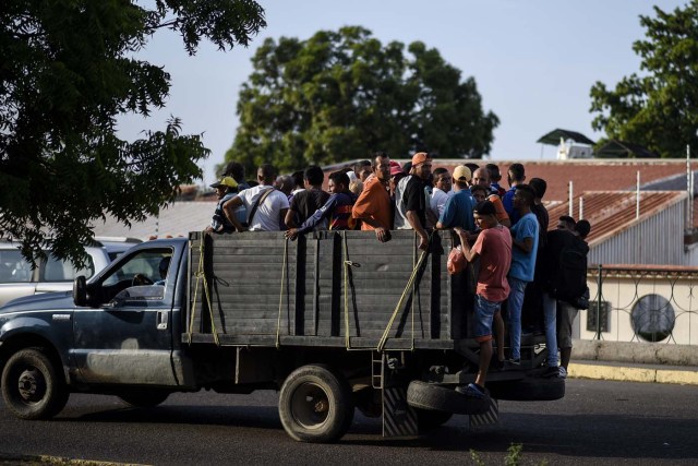 People travel on a private truck used as a means of transportation in Maracaibo, Venezuela on May 3, 2018. Amid blackouts, skyrocketing prices, shortage of food, medicine and transportation, Venezuelans go to elections next May 20 anguished to survive one of the worst crisis in the oil country. / AFP PHOTO / Federico PARRA