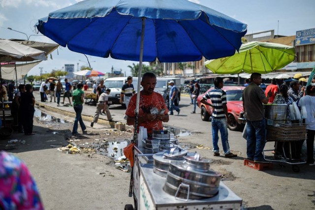 A peddler counts money in a street in Maracaibo, Venezuela on May 3, 2018. Amid blackouts, skyrocketing prices, shortage of food, medicine and transportation, Venezuelans go to elections next May 20 anguished to survive one of the worst crisis in the oil country. / AFP PHOTO / Federico PARRA