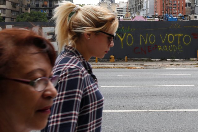 Las mujeres caminan más allá de los graffiti pintados en una valla en Caracas, Venezuela, 13 de mayo de 2018. Graffiti dice: "No voy a votar". Fotografía tomada el 13 de mayo de 2018. REUTERS / Carlos Jasso