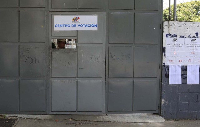 Un miembro de la milicia es visto detrás de una puerta en un colegio electoral durante las elecciones presidenciales en Caracas, Venezuela, el 20 de mayo de 2018. REUTERS / Marco Bello