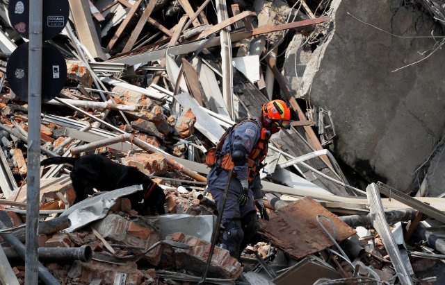 A rescue worker along with a sniffer dog searches for victims on a collapsed building in downtown Sao Paulo, Brazil May 1, 2018. REUTERS/Leonardo Benassatto