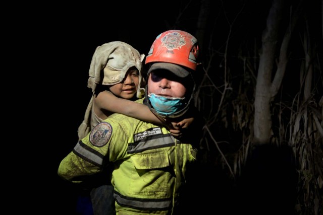 Un trabajador de rescate carga a un niño cubierto de ceniza después de que el volcán Fuego estalló violentamente en El Rodeo, Guatemala el 3 de junio de 2018. REUTERS / Fabricio Alonzo