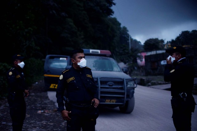 Los oficiales de policía con máscaras protegen el área después de que el volcán Fuego estalló violentamente en El Rodeo, Guatemala el 3 de junio de 2018. REUTERS / Fabricio Alonzo