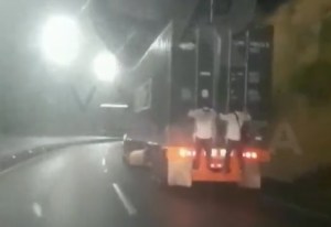 ¡Insólito! Par de imprudentes se fueron “guindando” en una gandola por la autopista Caracas-La Guaira (VIDEO)